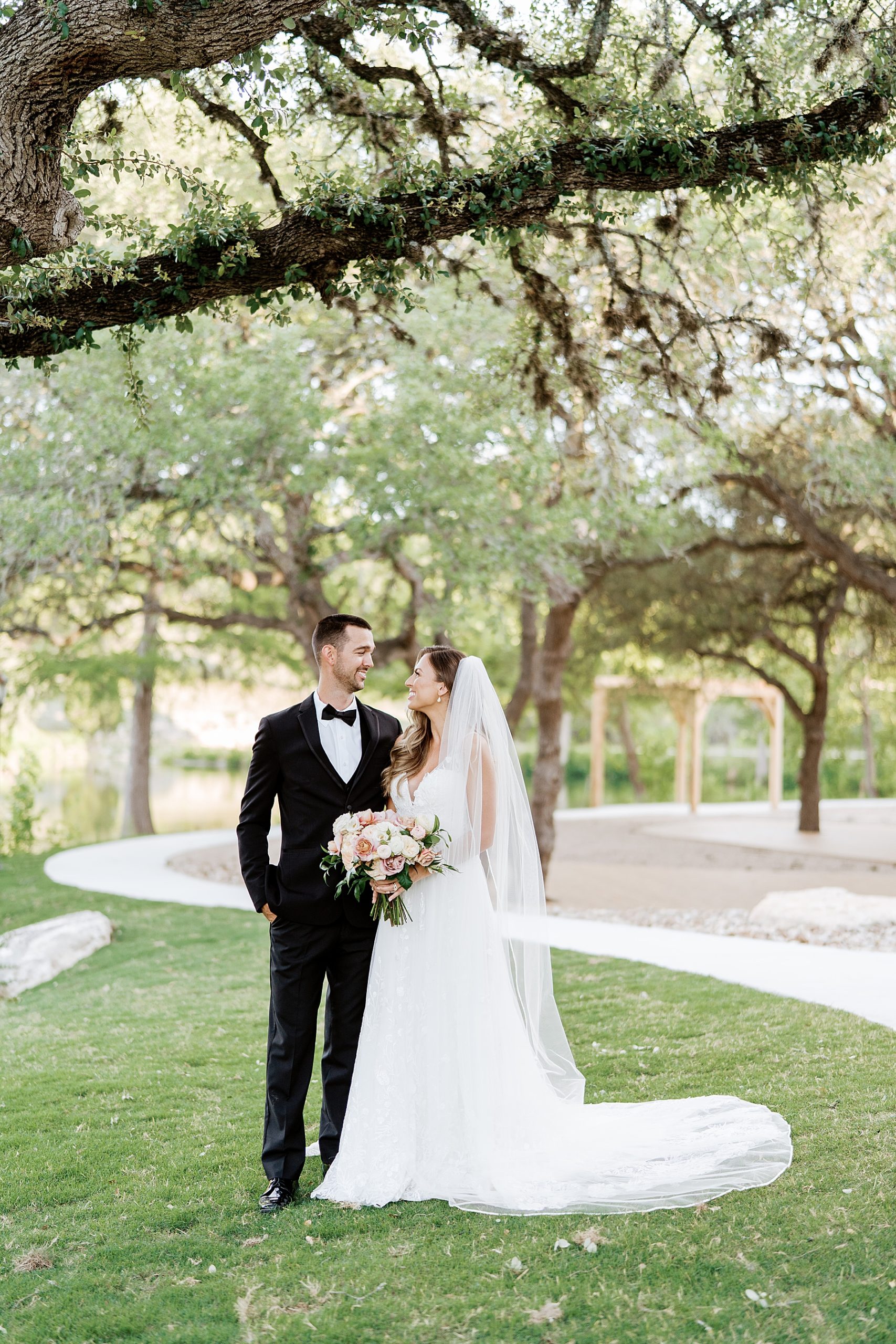 bride and groom smiling at each other on wedding day | Reiley and Rose | Central Texas Wedding Floral Designer | The Preserve at Canyon Lake Wedding Venue | classic wedding inspiration, chic wedding, pink wedding color scheme | via reileyandrose.com