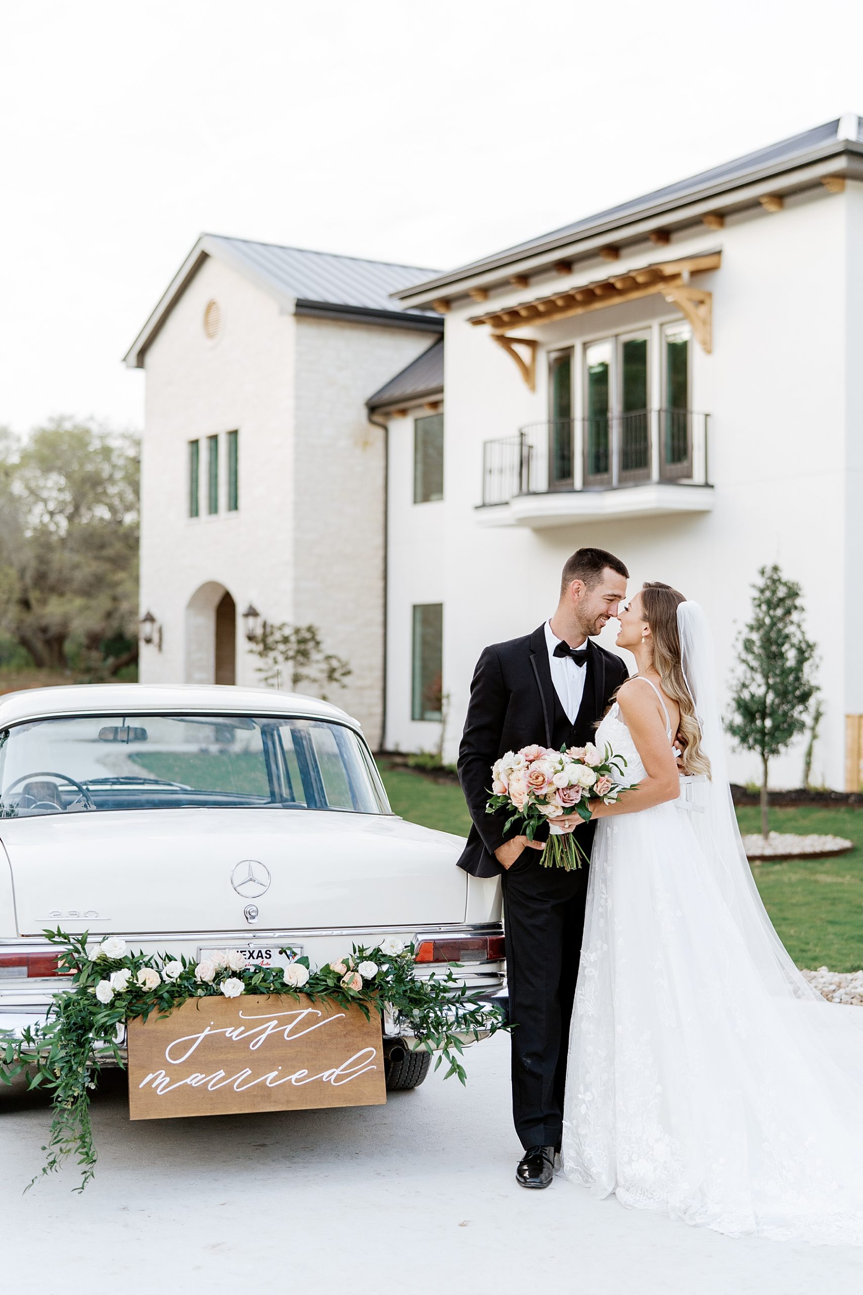 bride and groom smiling at each other next to vintage car on wedding day | Reiley and Rose | Central Texas Wedding Floral Designer | The Preserve at Canyon Lake Wedding Venue | classic wedding inspiration, chic wedding, pink wedding color scheme | via reileyandrose.com