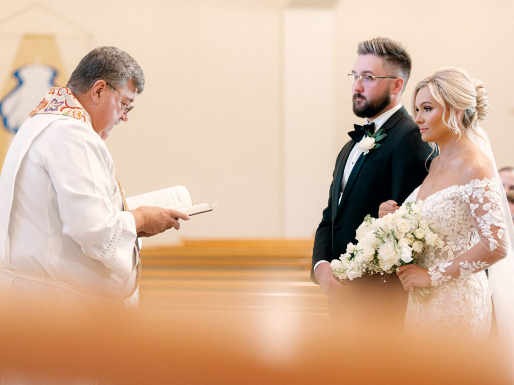 Bride and Groom standing at the altar with Preacher in church  | Chandelier of Gruene Wedding | Modern Black and White Chic Wedding | 