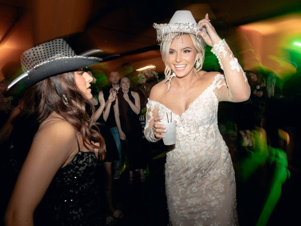 bride wearing cowboy hat on dance floor  | Chandelier of Gruene Wedding | Modern Black and White Chic Wedding | 