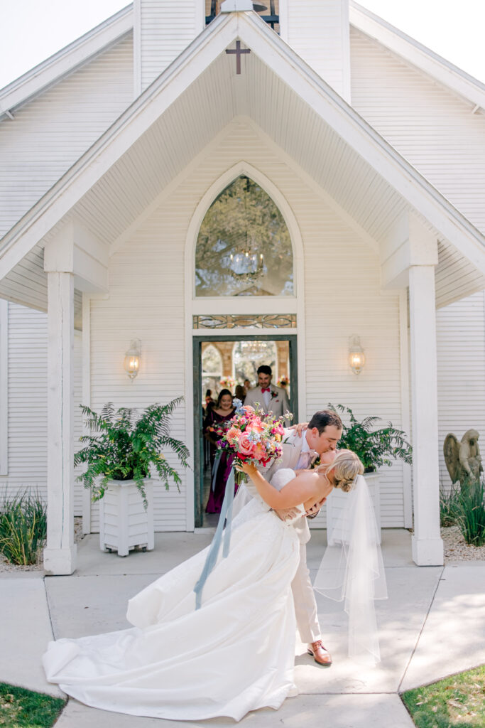 bride and groom outside white chapel