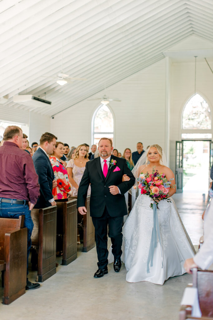 father of the bride and bride walk down the aisle
