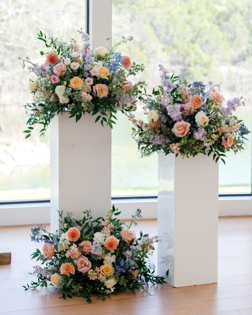 Lush ceremony pedestal arrangements with peach, lavender, and blush blooms The Preserve at Canyon Lake wedding