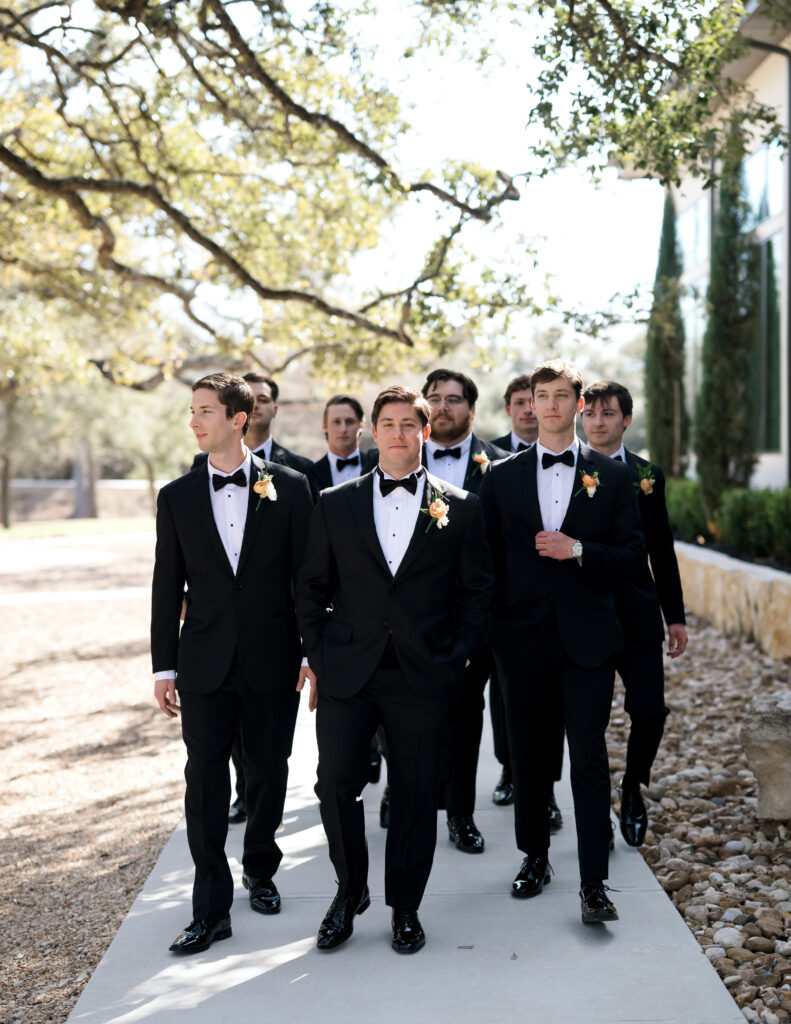 Groomsmen in black tuxes walking together outside