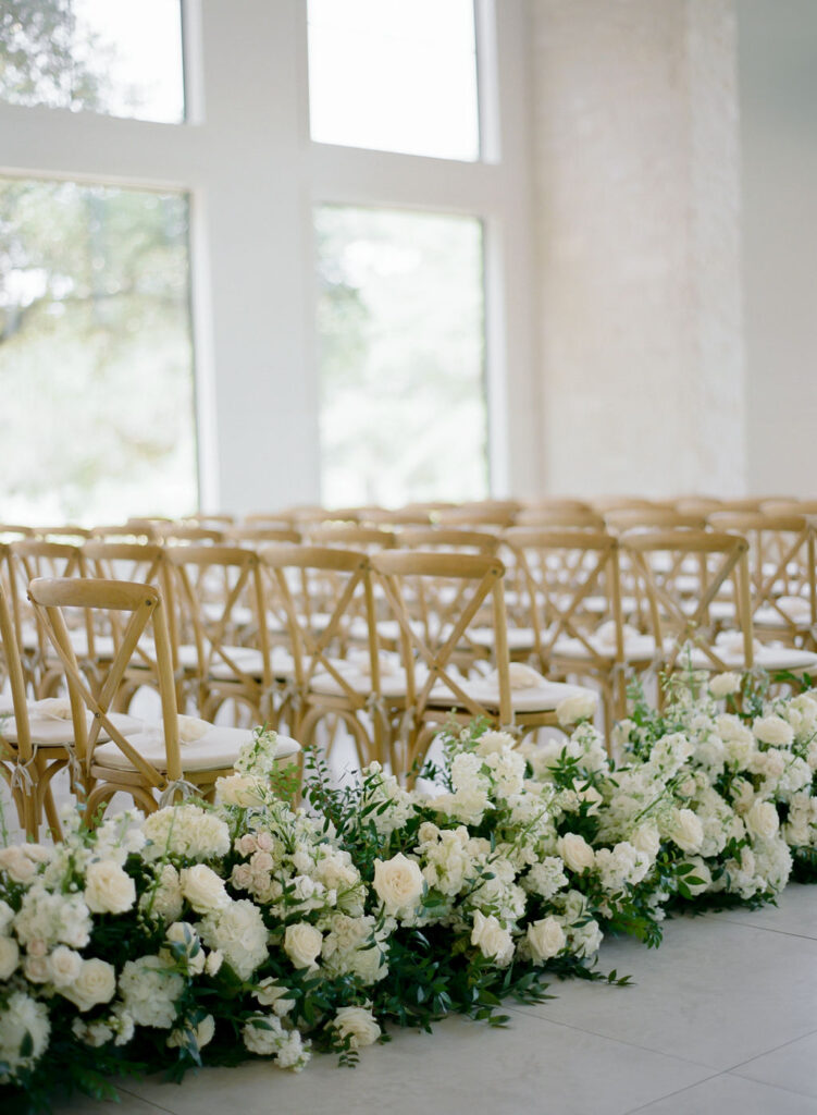 A solid floral runner of white and green wedding flowers lined the aisle