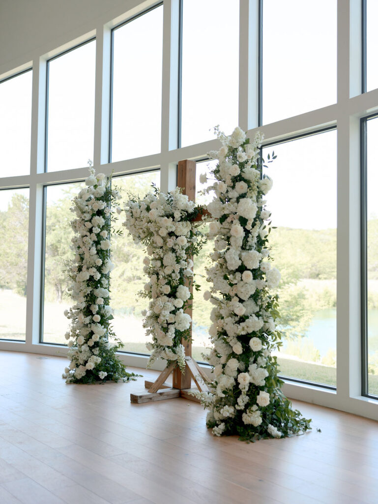 This ceremony design featured a duo of large white floral pillars with a cross at the center
