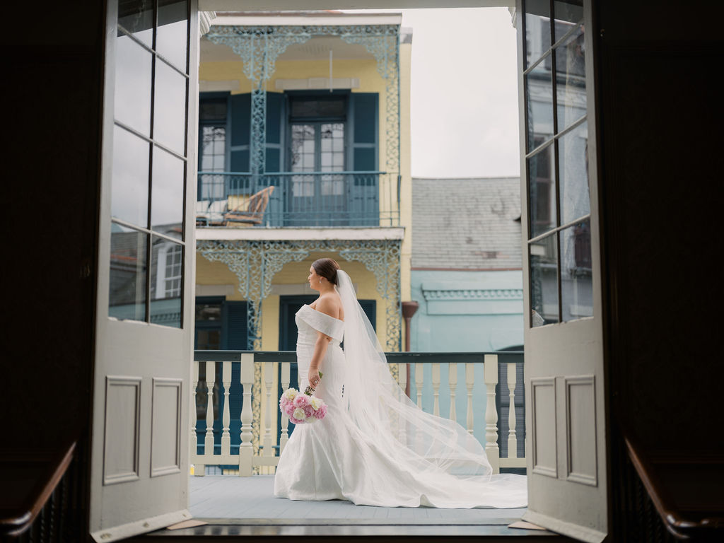 A bride posing for a portrait in New Orleans holding her wedding flowers.