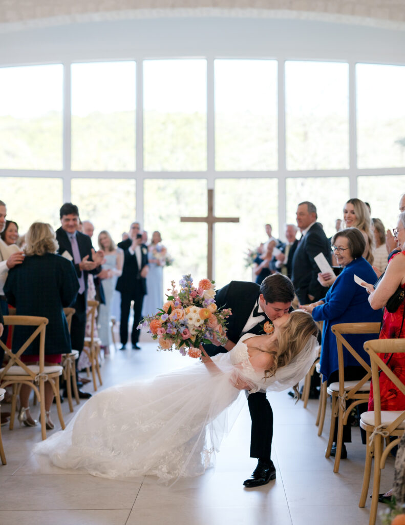 Newlyweds kissing at end of aisle